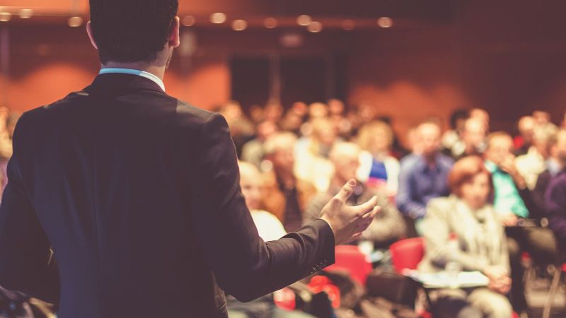 Das Bild zeigt eine präsentierende Person vor Zuhörenden.