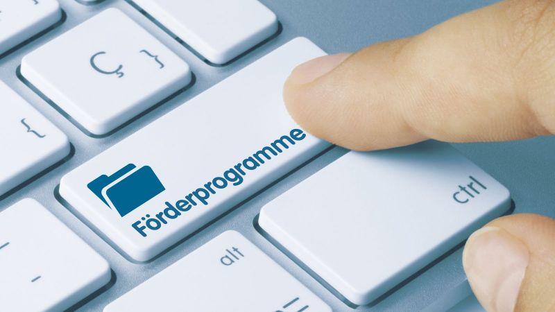 Tastatur mit der Beschriftung Förderprogramme auf einer Taste, die von einem Zeigefinger gedrückt wird.
