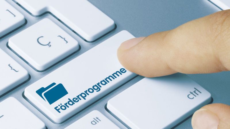 Tastatur mit der Beschriftung Förderprogramme auf einer Taste, die von einem Zeigefinger gedrückt wird