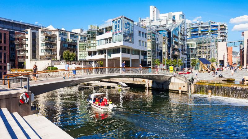 Das Bild zeigt eine Brücke über einen Fluss in einer modernen Stadt.