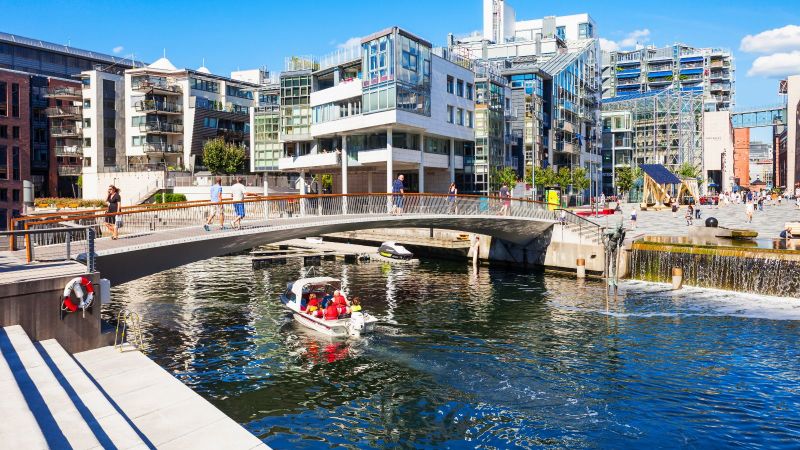 Das Bild zeigt eine Brücke über einen Fluss in einer modernen Stadt.