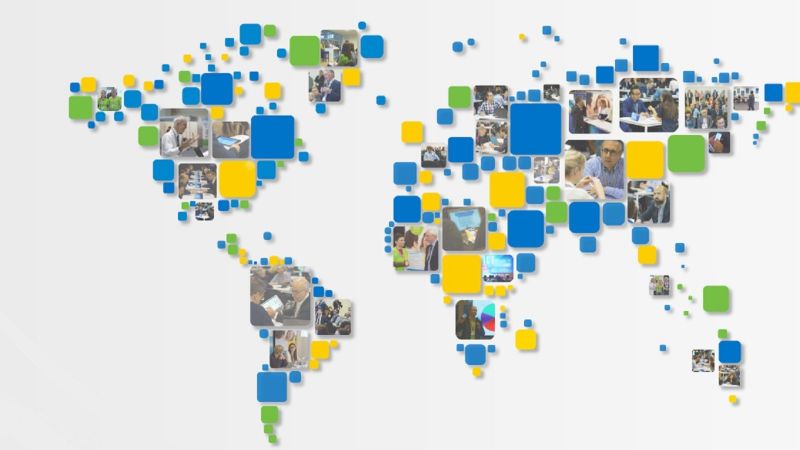 Weltkarte geformt aus quadratischen Kacheln in den Farben von IDEAL-IST (grün, gelb und blau) und mit Fotos einzelner Projekt-Partnerinnen oder Projektpartner bei verschiedenen Aktivitäten