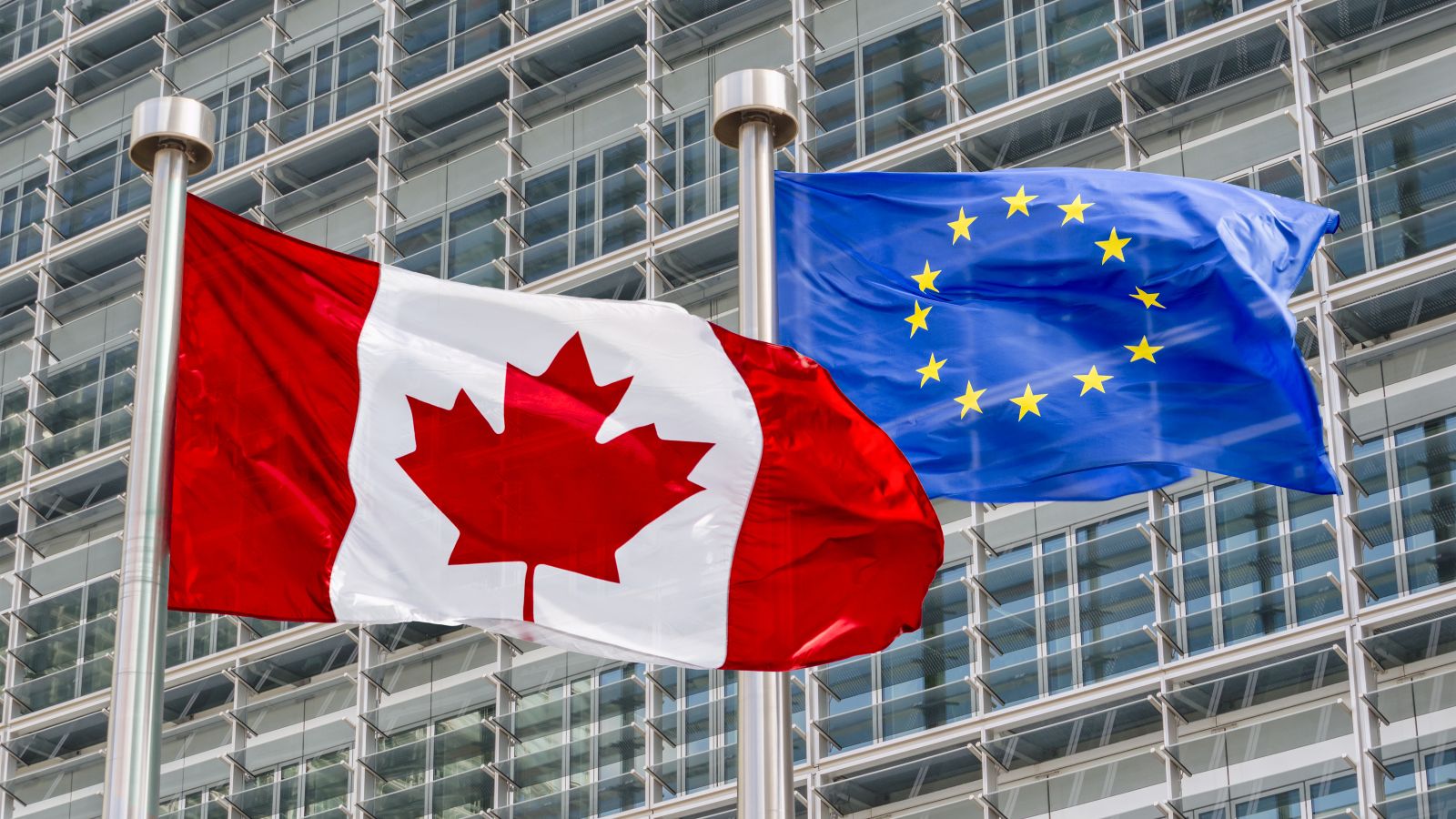 Eine kanadische und eine europäische Fahne wehen im Wind.
