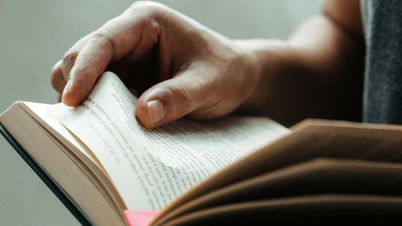 Das Bild zeigt Hände, die in einem Buch blättern.