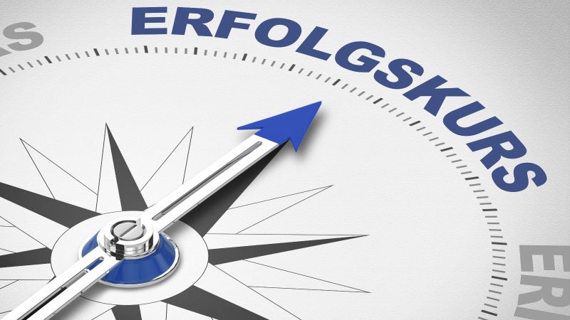 Das Bild zeigt einen Kompass, dessen Nadel auf das Wort 'Erfolgskurs' zeigt.