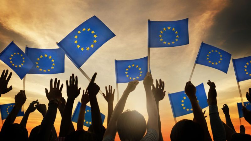 Hände, die Europa-Flaggen (blau mit einem Kreis aus goldenen Sternen) schwenken