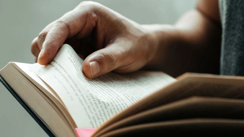 Das Bild zeigt ein ausgeschlagenes Buch in dem eine Person liest.