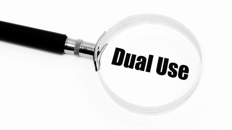 Das Bild zeigt eine Lupe, mit der der Begriff „Dual Use“ vergrößert wird.