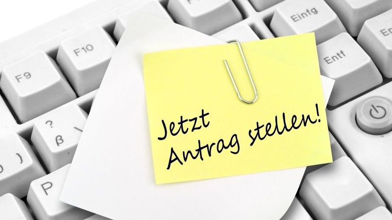 Eine Post-It Erinnerung auf einer Tastatur, die daran erinnert den Antrag jetzt zu stellen.