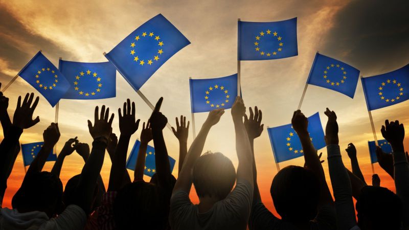 Das Bild zeigt eine Gruppe Menschen, die mit kleinen Europa-Flaggen wedeln.