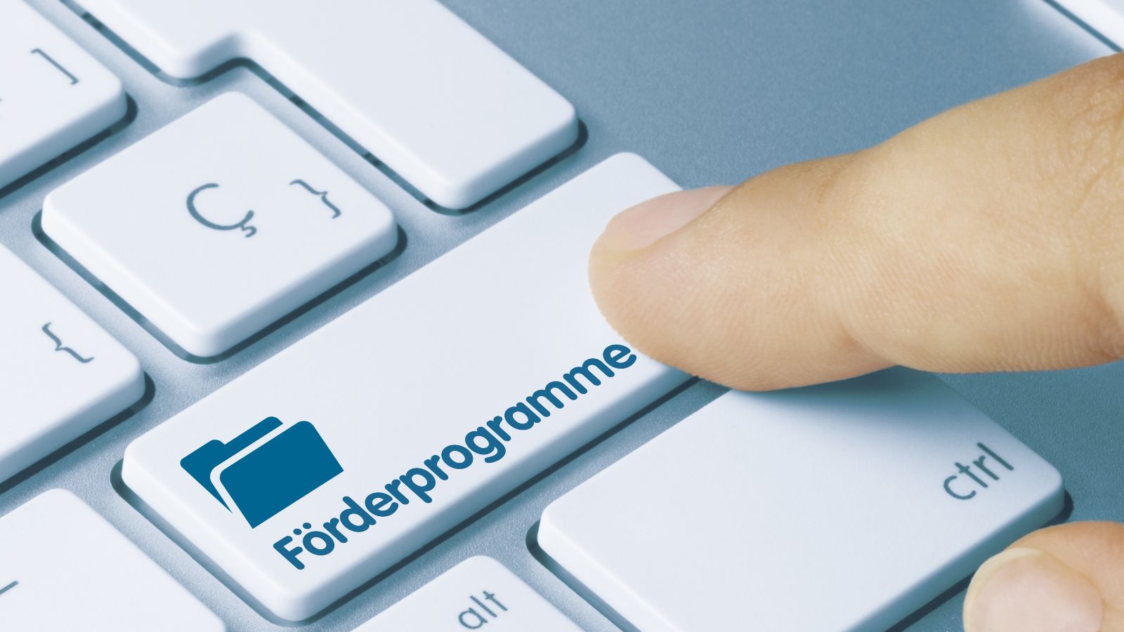 Das Bild zeigt eine Laptoptastatur auf der ein Finger eine Taste drückt, die als 'Förderprogramme' beschriftet ist. Internetseite, Newsletter, Präsentationen, social Media
