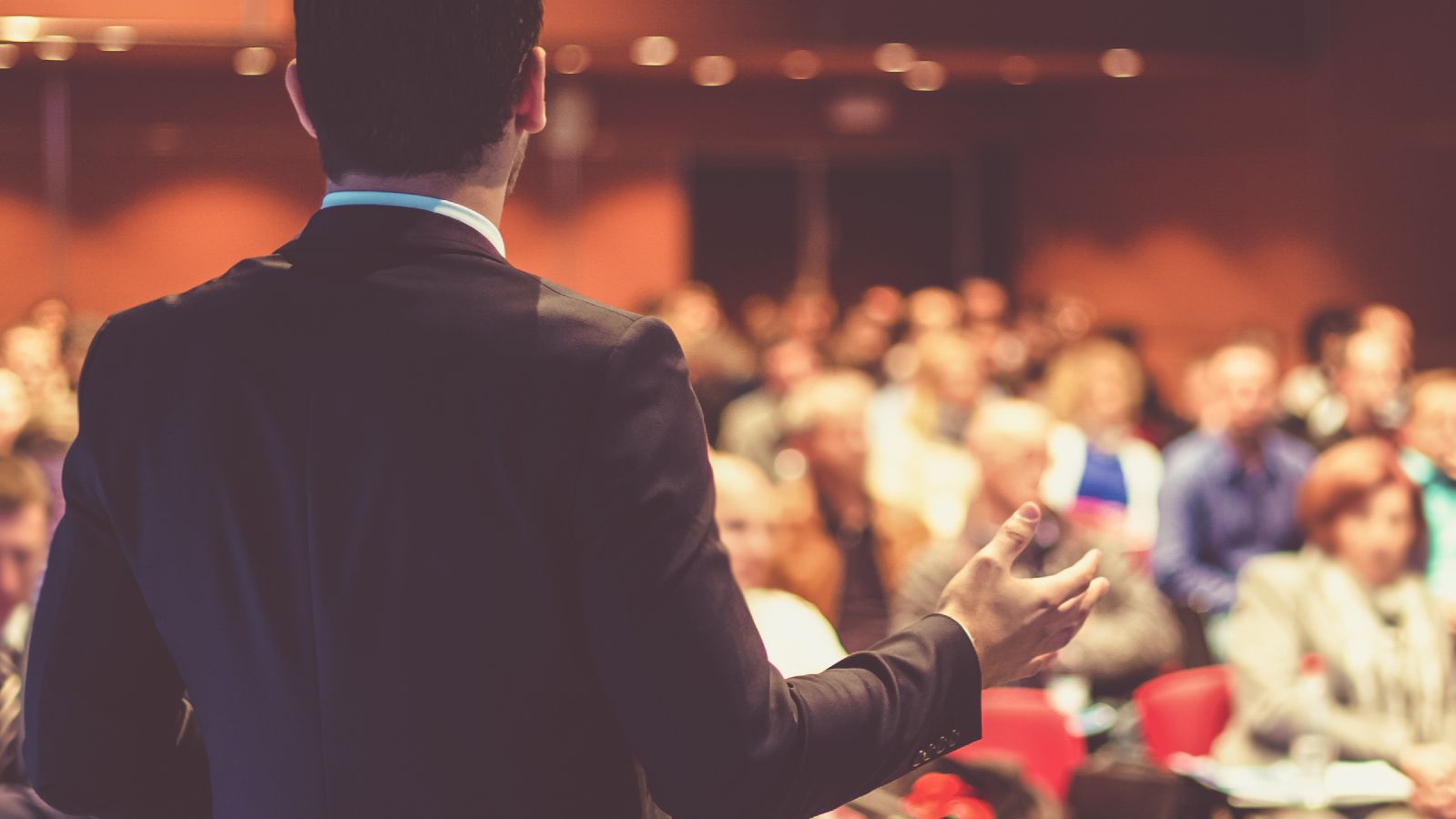 Das Bild zeigt eine präsentierende Person vor Zuhörenden.