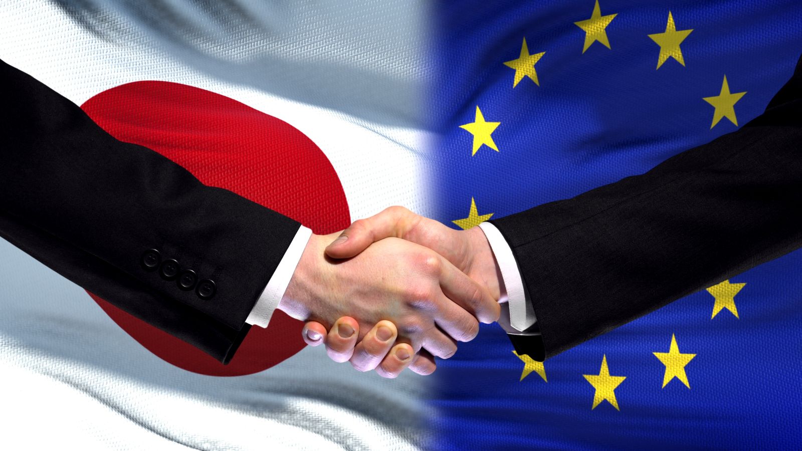 Handschlag zweier Personen vor dem Hintergrund der Flaggen der EU und Japan 